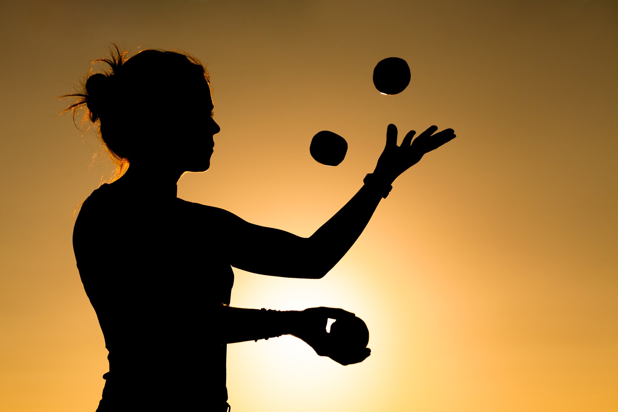 Femme jonglant avec des balles au soleil couchant